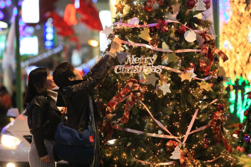 Deux Asiatiques décorent un sapin de Noël